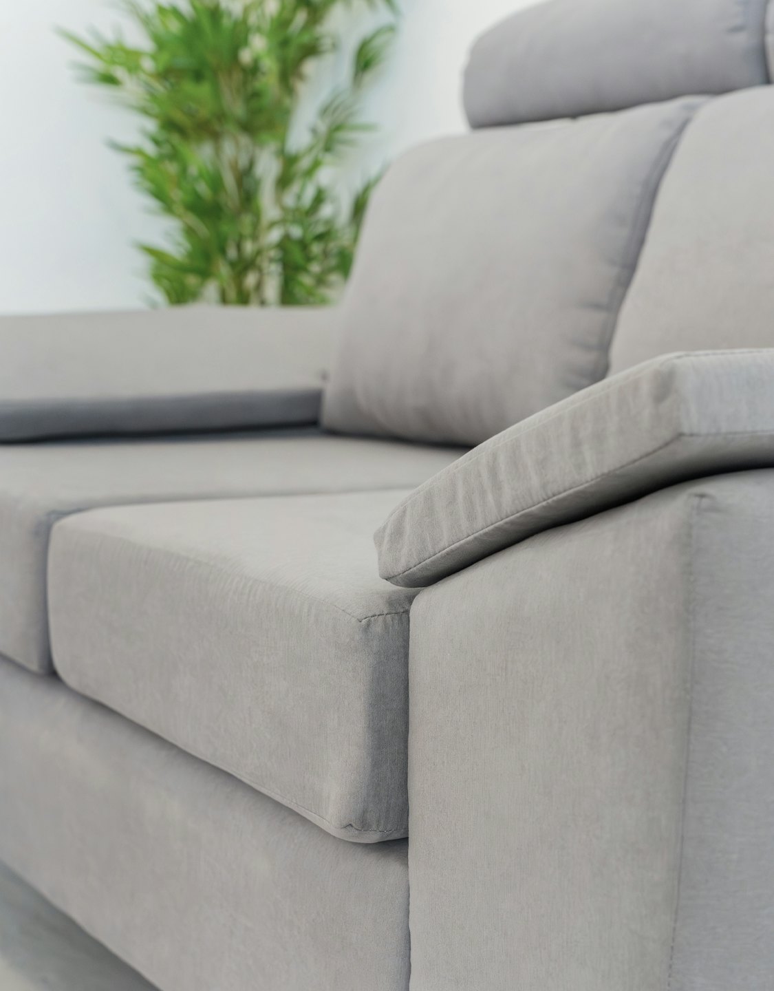 Modern light gray fabric sofa armrest in a living room.